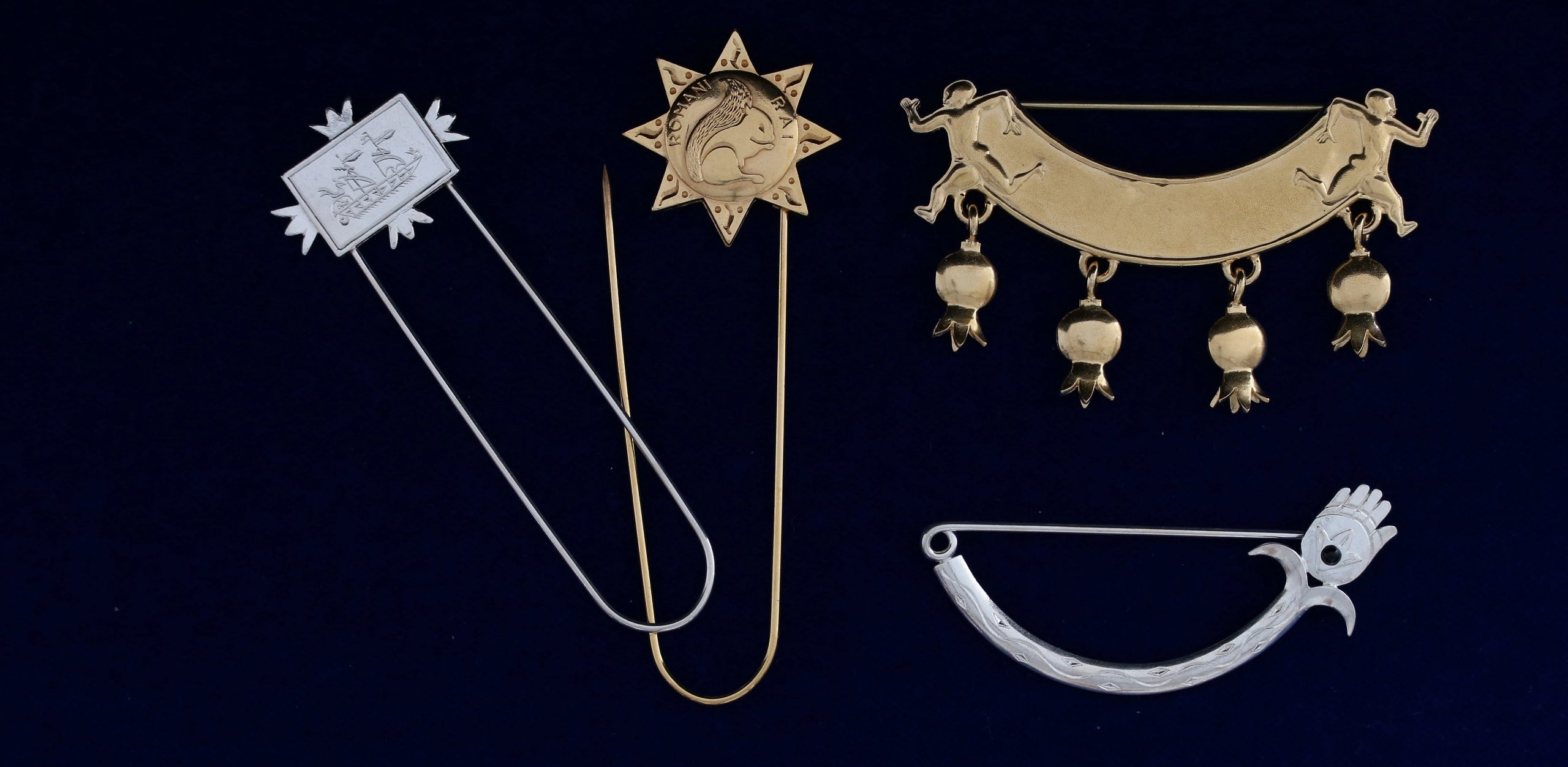 Wright & Teague archive pins. Silver and 18ct gold. On A Dark Blue Table.