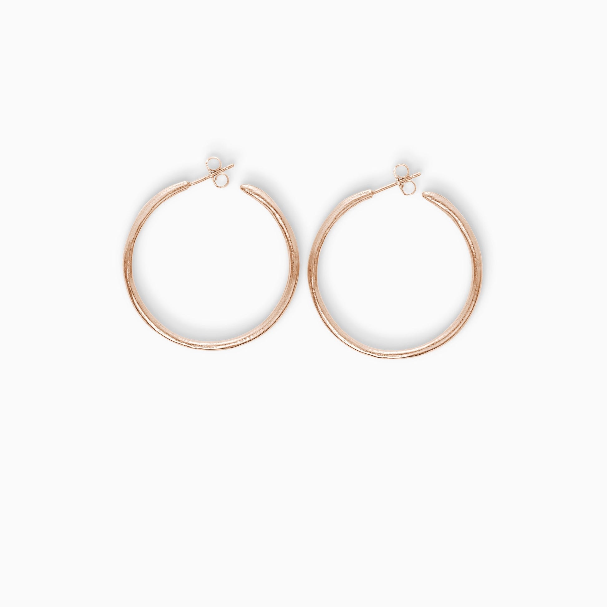A pair of 18ct Fairtrade rose gold  round hoop earrings with a stud fastening. Organic texture and irregular profile. 36mm outside diameter.