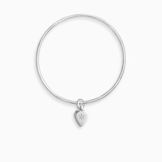 A recycled Silver smooth heart shaped charm engraved with a 6 petal flower, freely moving on a round wire bangle. Charm 15mm x 8mm. Bangle 63mm inside diameter x 2mm round wire.