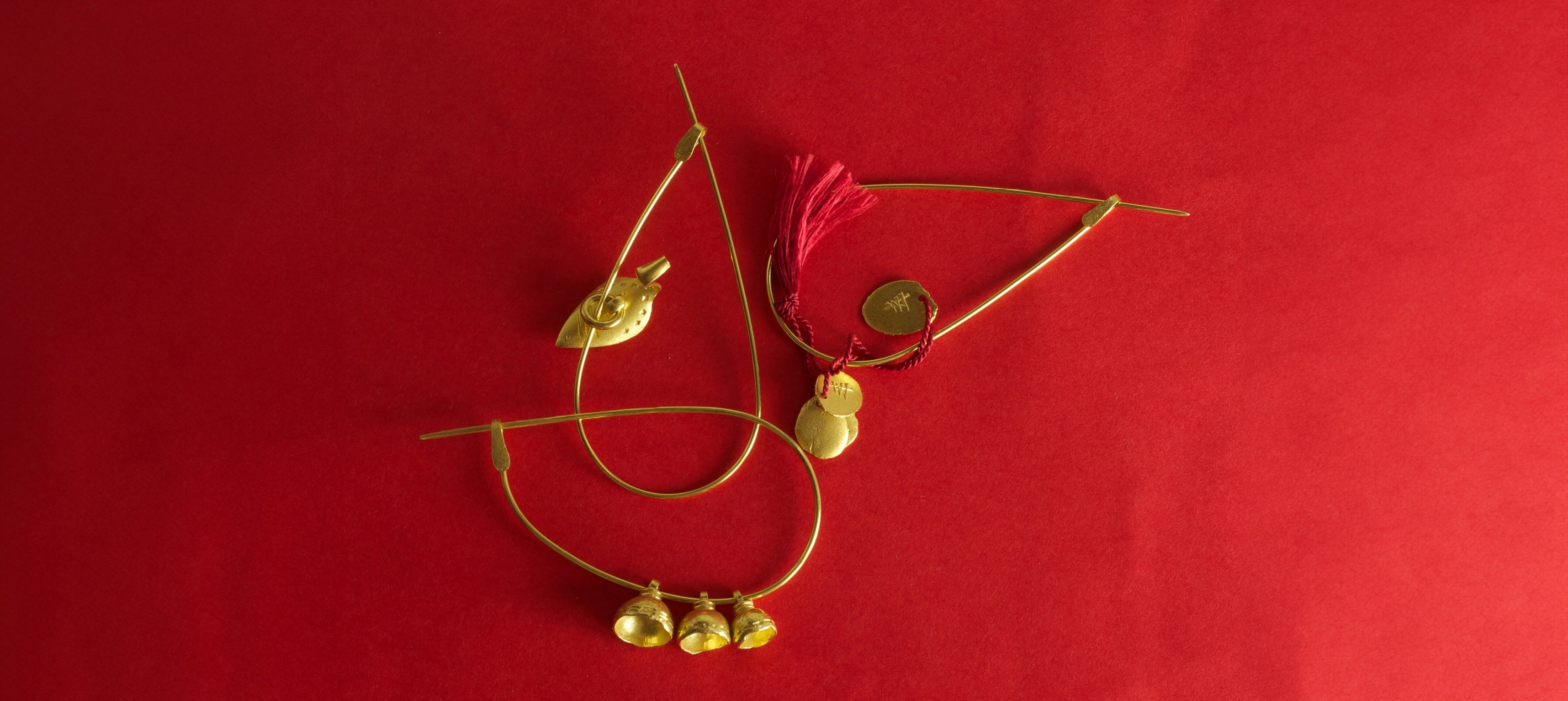 Wright & Teague Nuba pins. 18ct Fairtrade gold. On a red background.