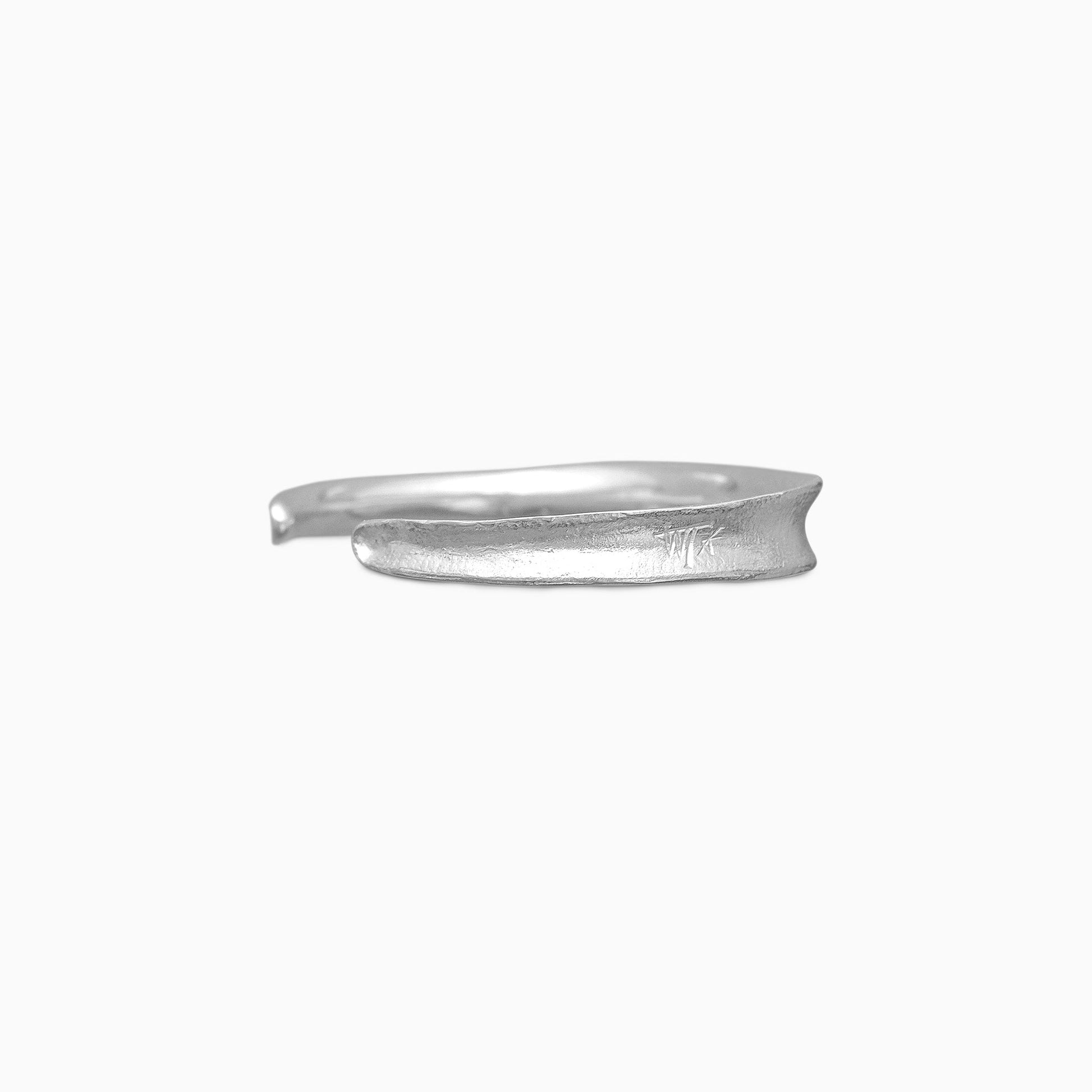 A recycled Silver Cuff bangle fitting close to wrist. Concave and textured. Open ended to get on and off. Width 8mm. Inside oval diameter 58mm. 