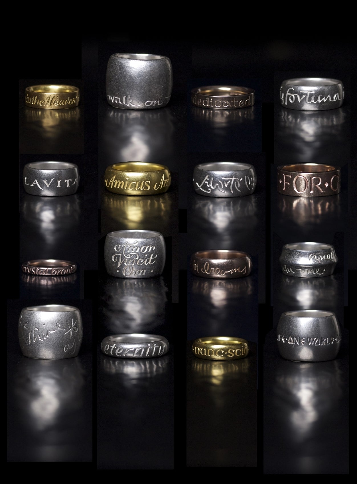 Wright & Teague inscription rings. 16 Rings, 4 rows of 4. Reflecting on a high polished black surface.
