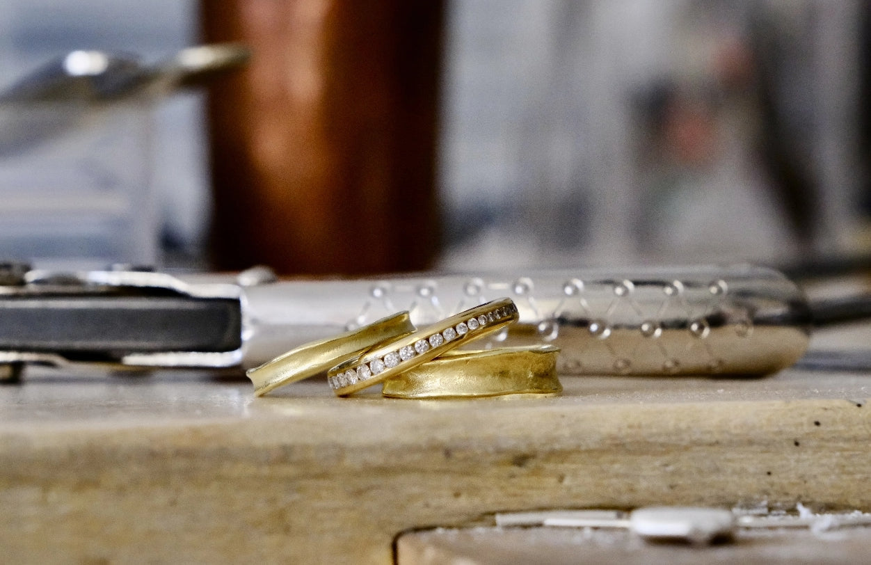 Celestial and Iliad rings in the making. 18ct yellow gold and diamonds. Laying on a work bench.