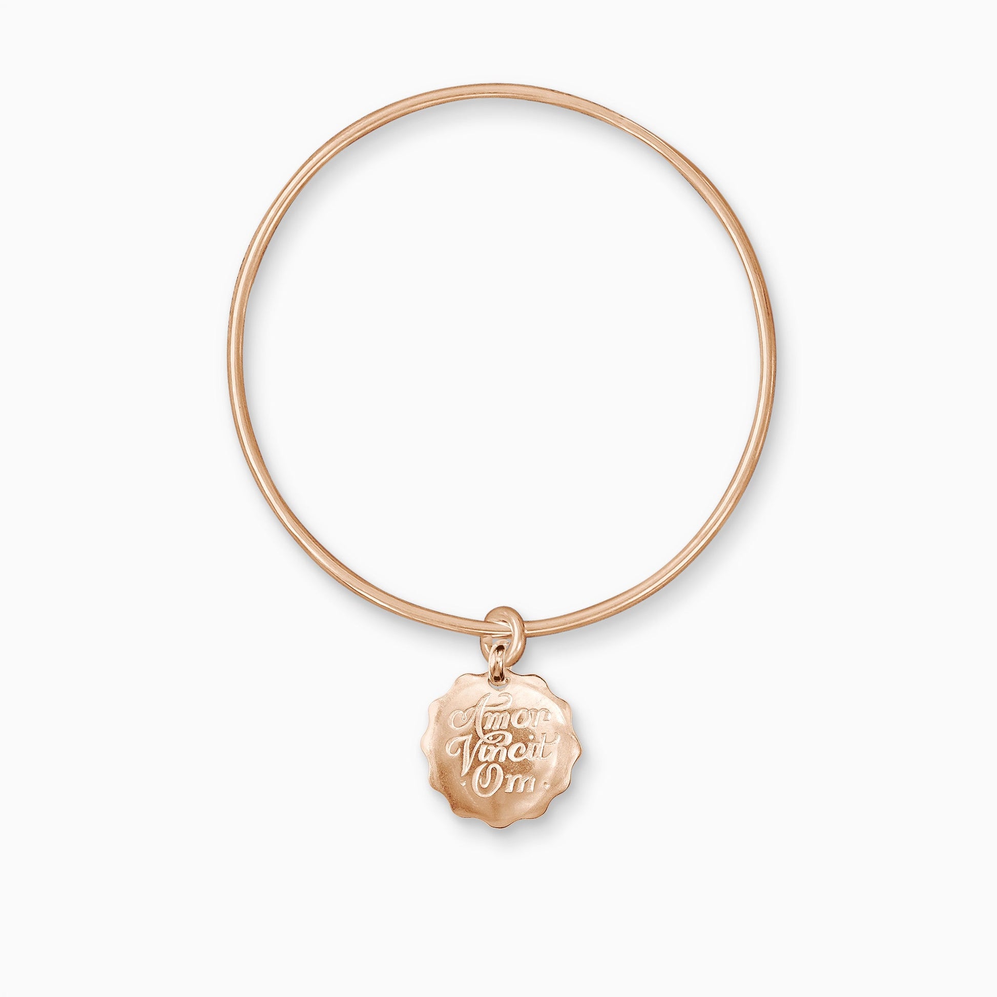 An 18ct Fairtrade rose gold round, smooth charm with a wavy edge engraved with ‘Love Conquers All’ in Latin, freely moving on a round wire bangle.  Charm 22mm. Bangle, 63mm inside diameter x 2mm round wire.