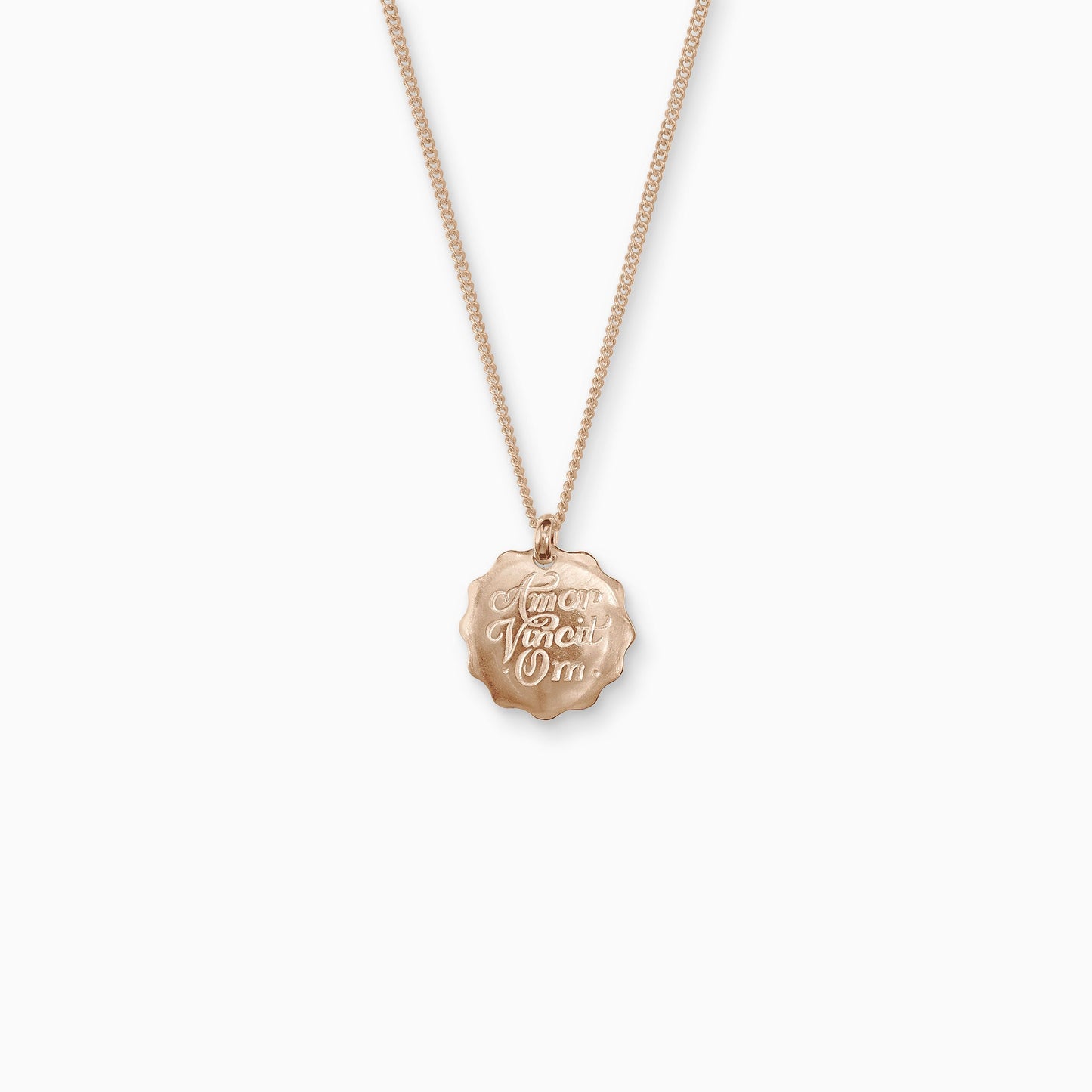 18ct Fairtrade rose gold round 22mm diameter charm on a 45cm fine curb chain. The pendant is smooth with a wavy outside edge. Amor Vincit Om, the Medieval Latin for Love Conquers All  is inscribed on the front in a Copperplate script. 