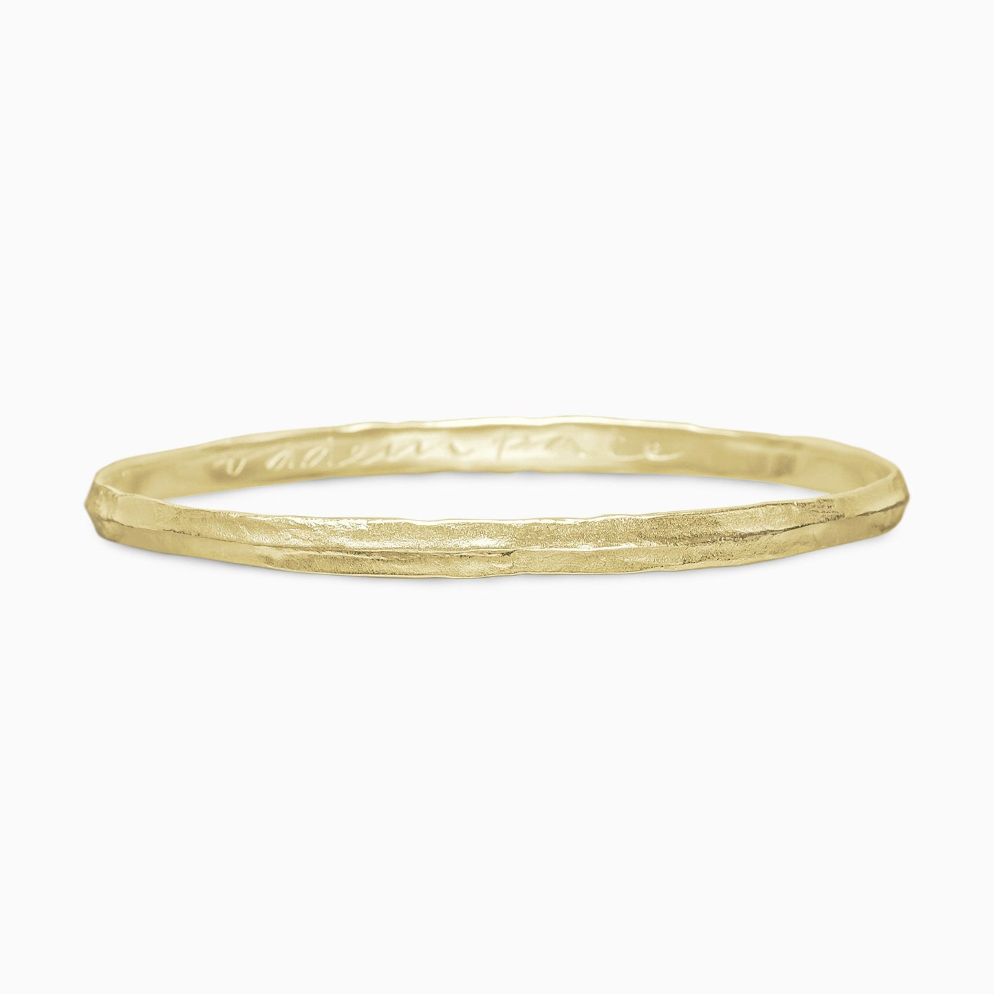 An 18ct Fairtrade yellow gold bangle rising to a central ridge, engraved inside ‘VAde in Pace’ which is ‘Go in Peace’ in Latin. Width 5mm. Inside diameter 63mm.