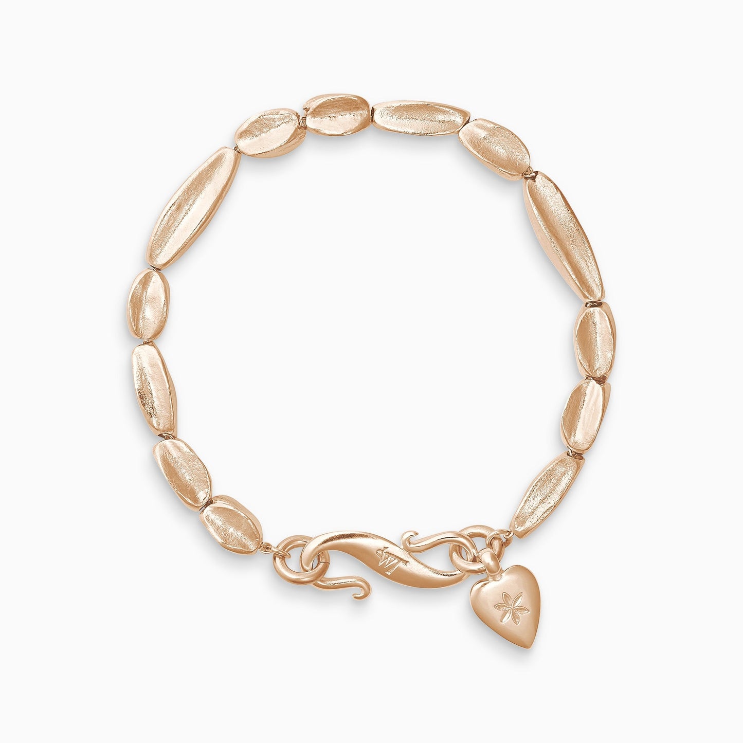 An 18ct Fairtrade rose gold bracelet of handmade organic, concave, square section textured ‘Baluba’ beads. Finished with a smooth heart shaped charm, engraved with a 6 petal flower and our signature ’S’ clasp. Bracelet length 210mm. Beads varying lengths from 10mm to 40mm. Cross section of each bead approximately 6mm.