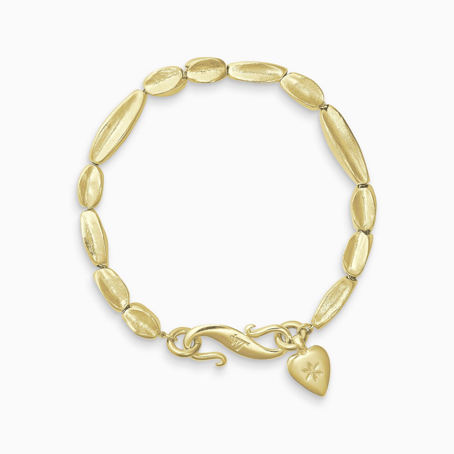 An 18ct Fairtrade yellow gold bracelet of handmade organic, concave, square section textured ‘Baluba’ beads. Finished with a smooth heart shaped charm, engraved with a 6 petal flower and our signature ’S’ clasp.Bracelet length 190mm.. Beads varying lengths from 10mm to 40mm. Cross section of each bead approximately 6mm.