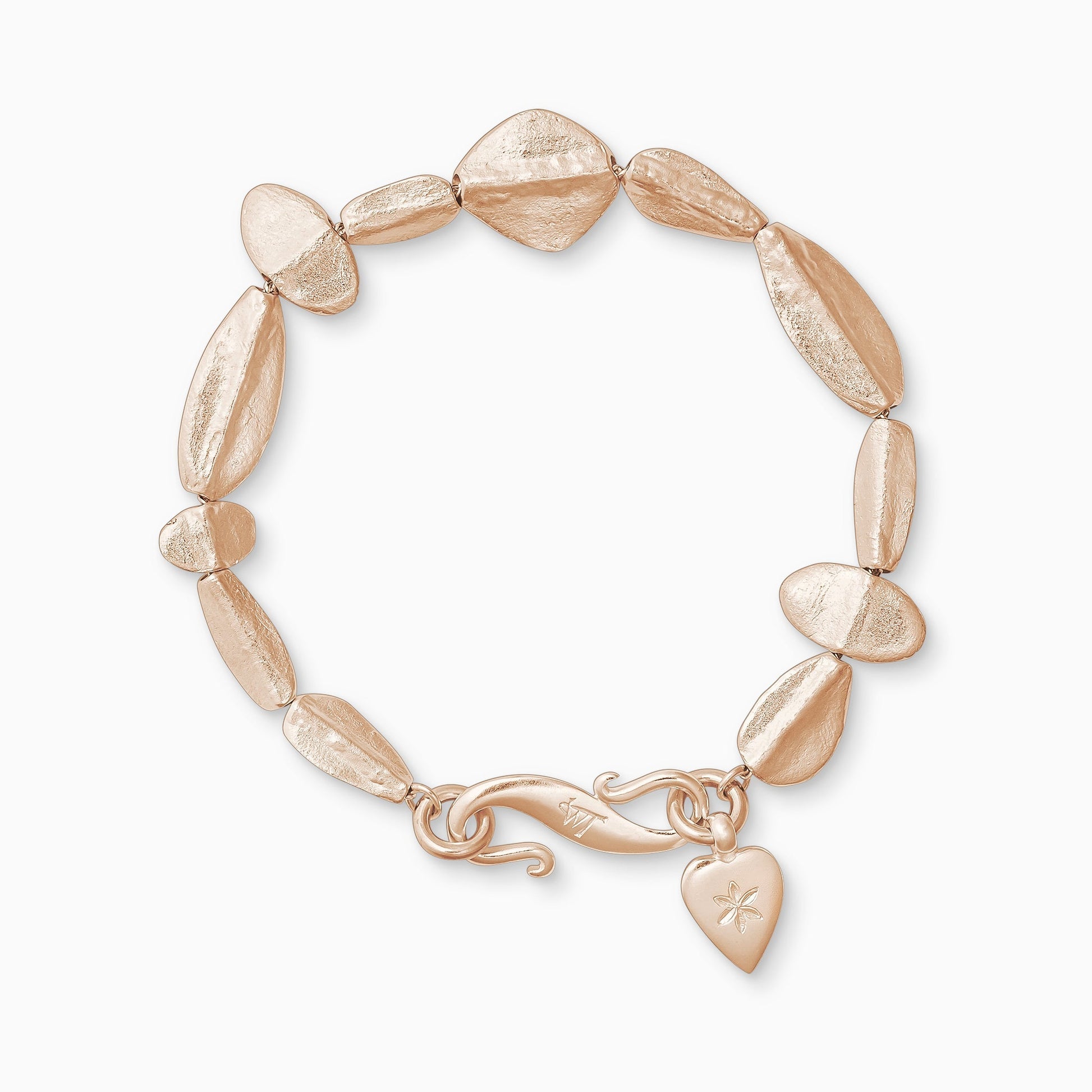 An 18ct Fairtrade rose gold bracelet of handmade textured beads with a central ridge.  Finished with a smooth heart shaped charm engraved with a 6 petal flower and our signature ’S’ clasp. Bracelet length 210mm.. Beads varying sizes from 11mm x 6mm to 35mm x 15mm.
