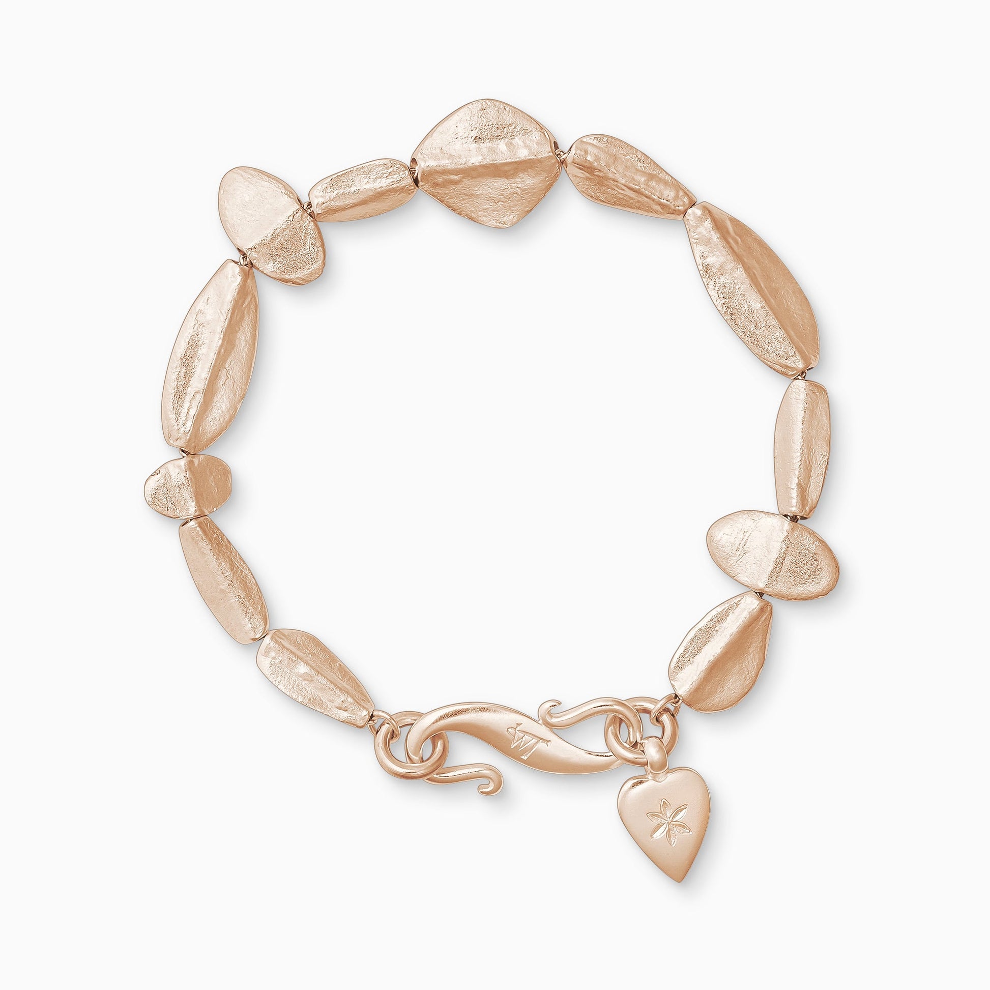 An 18ct Fairtrade rose gold bracelet of handmade textured beads with a central ridge.  Finished with a smooth heart shaped charm engraved with a 6 petal flower and our signature ’S’ clasp. Bracelet length 190mm.. Beads varying sizes from 11mm x 6mm to 35mm x 15mm.