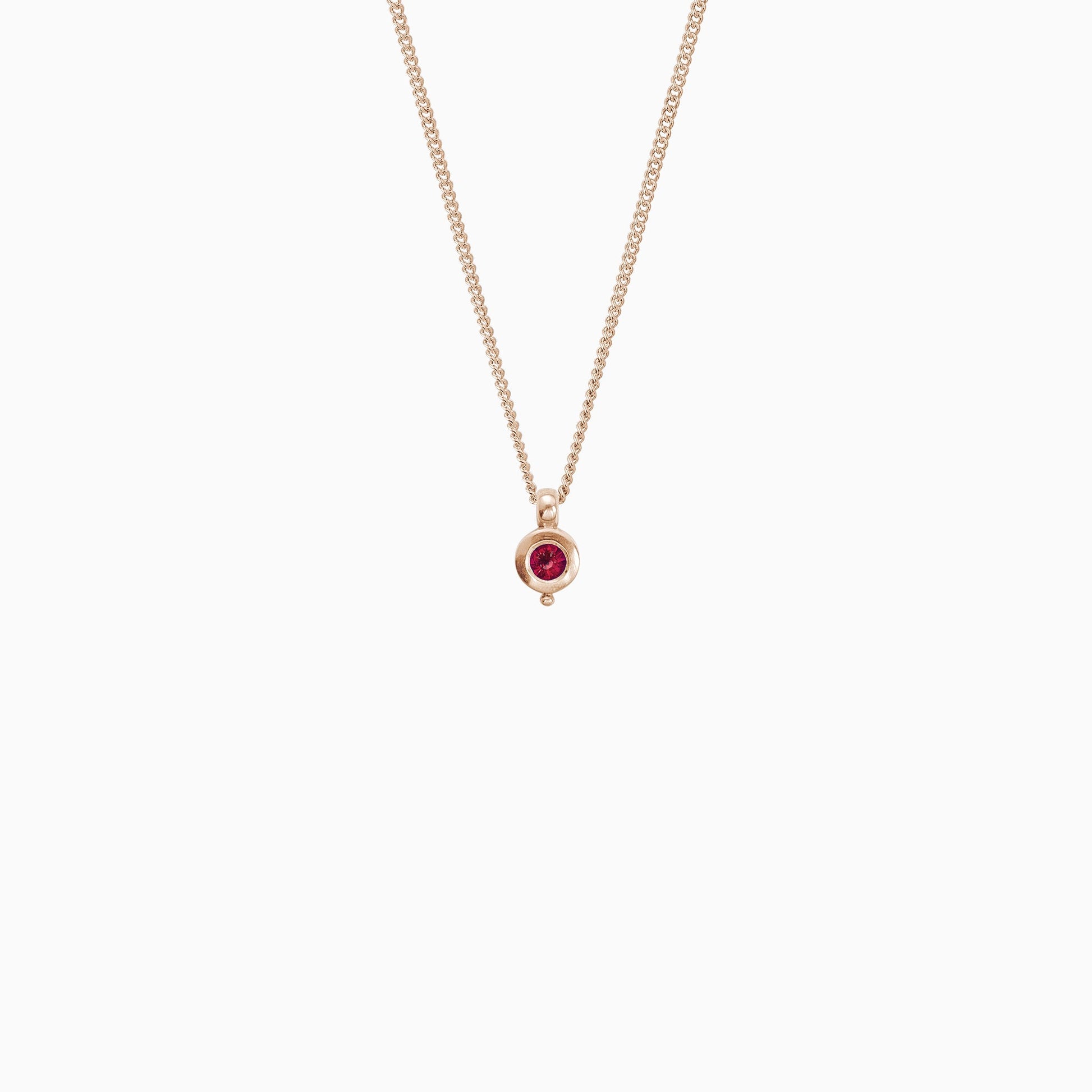 18ct Fairtrade rose gold round pendant 12mm  x 7mm with small round bead attached below on a 45cm fine curb chain. Set with a 4mm round ruby.