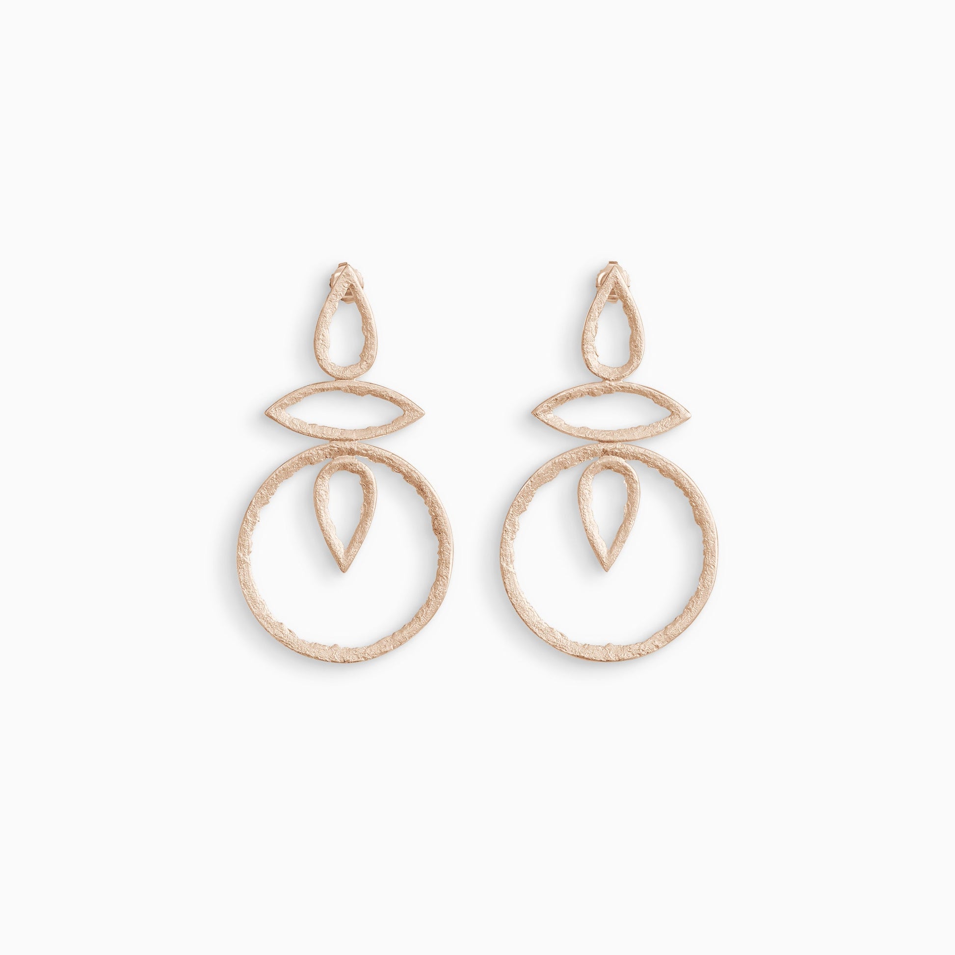 A large pair of 18ct Fairtrade rose gold drop earrings with a stud ear fitting. A teardrop shape connects a lozenge shape to a circle in a line. Another teardrop shape in reverse is inside the circle. These open strongly textured shapes have smooth outside edges and fragmented inside edges. 46mm x 26mm.