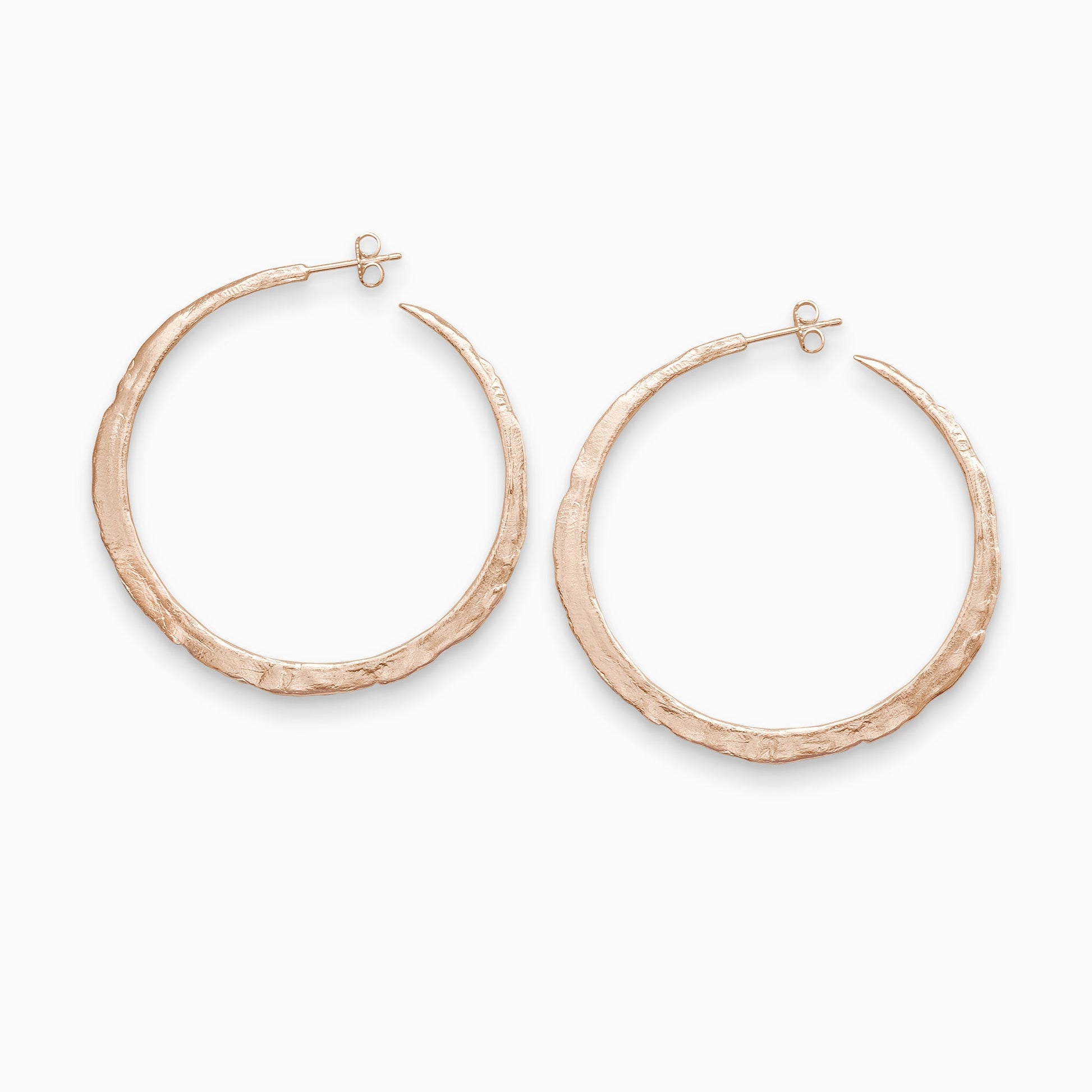 A pair of 18ct Fairtrade rose gold  round hoop earrings with a stud fastening. Organic texture and and tapering from bottom centre to the top. 55mm outside diameter.