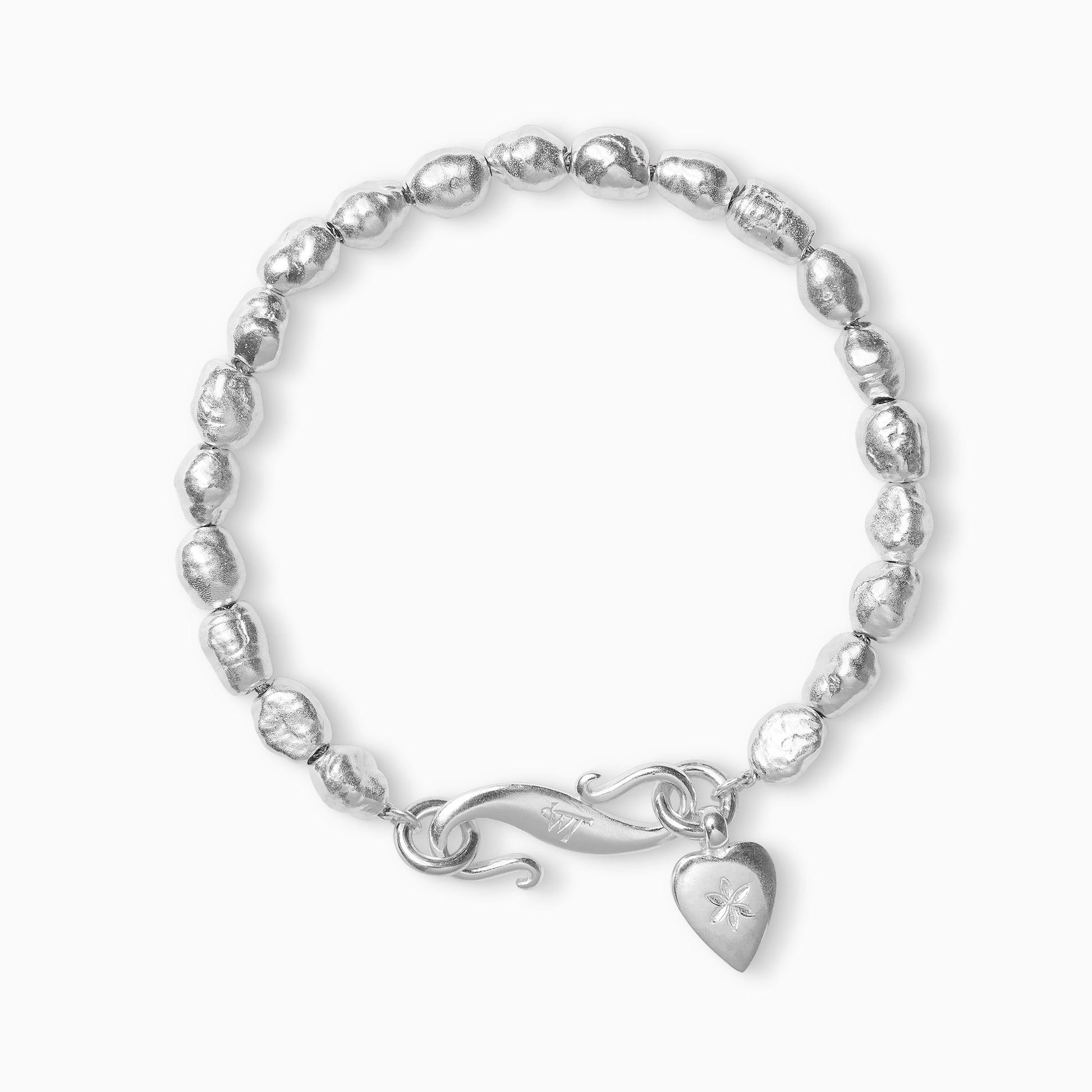 A recycled Silver bracelet of handmade irregular pearl shaped textured beads with a smooth heart shaped charm engraved with a 6 petal flower and our signature ’S’ clasp.  Bracelet length 210mm.. Beads varying approximately 8mm x 6mm.