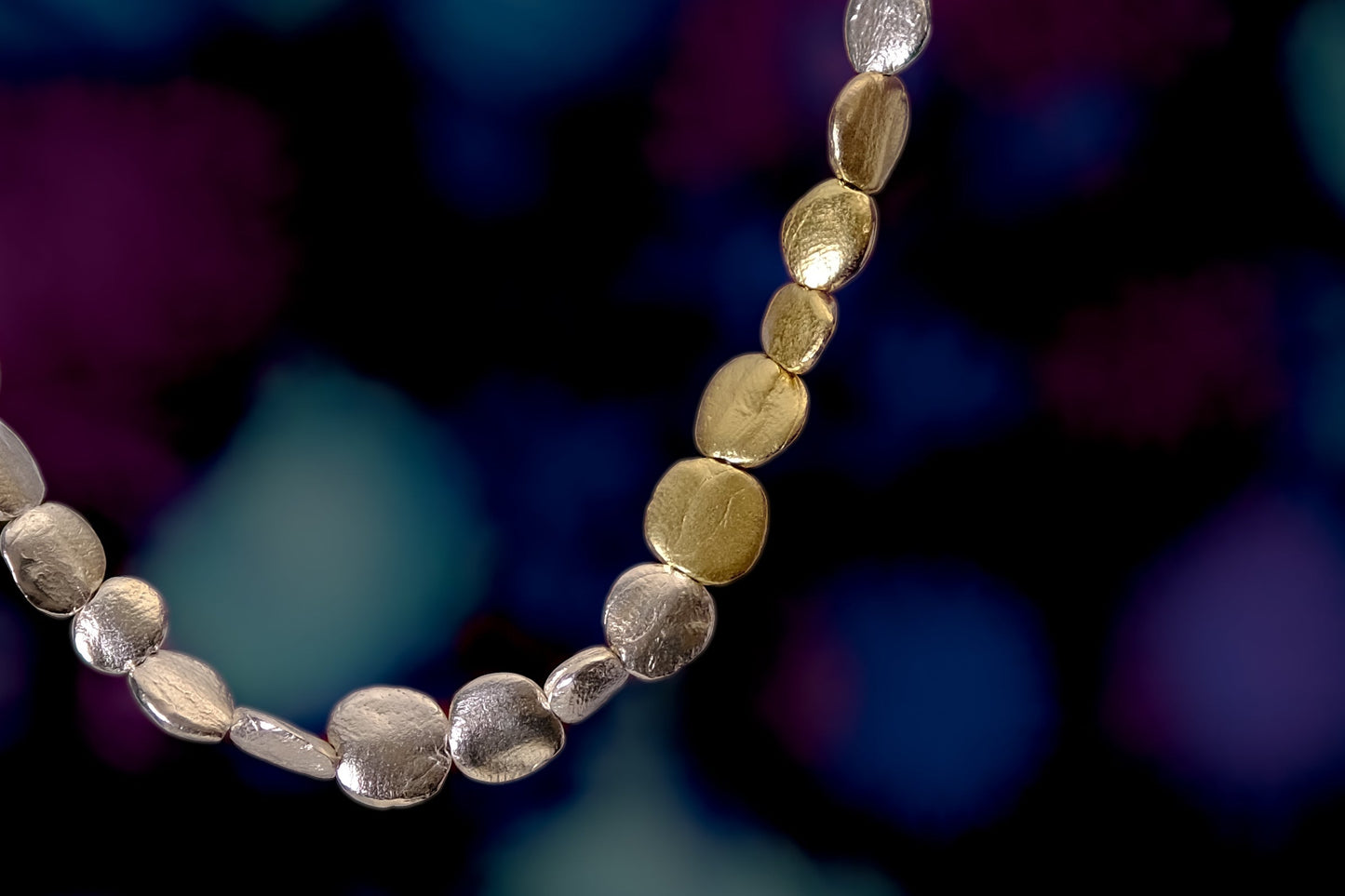 A photograph of part of a silver mystic bead bracelet with the addition of 5 18ct yellow gold beads.
